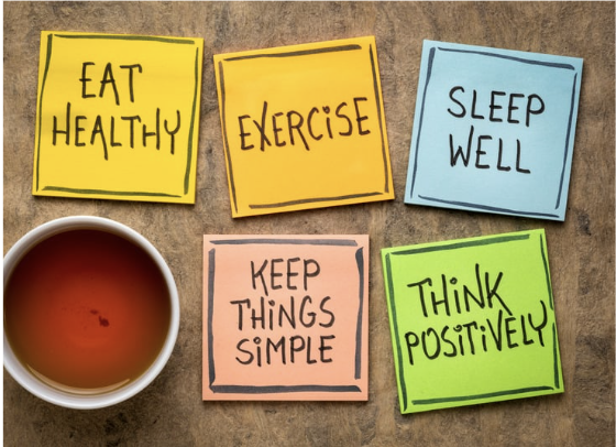 An above view of sticky notes that read: "eat healthy", "exercise", "sleep well", "keep things simple", and "think positively", to represent the lifestyle of living well.