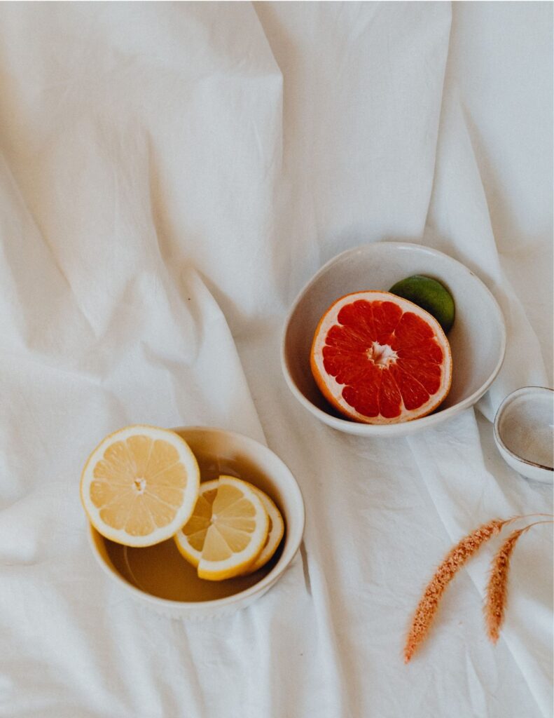 An above view of bowls sitting on a white backdrop, containing grapefruit and lemon.