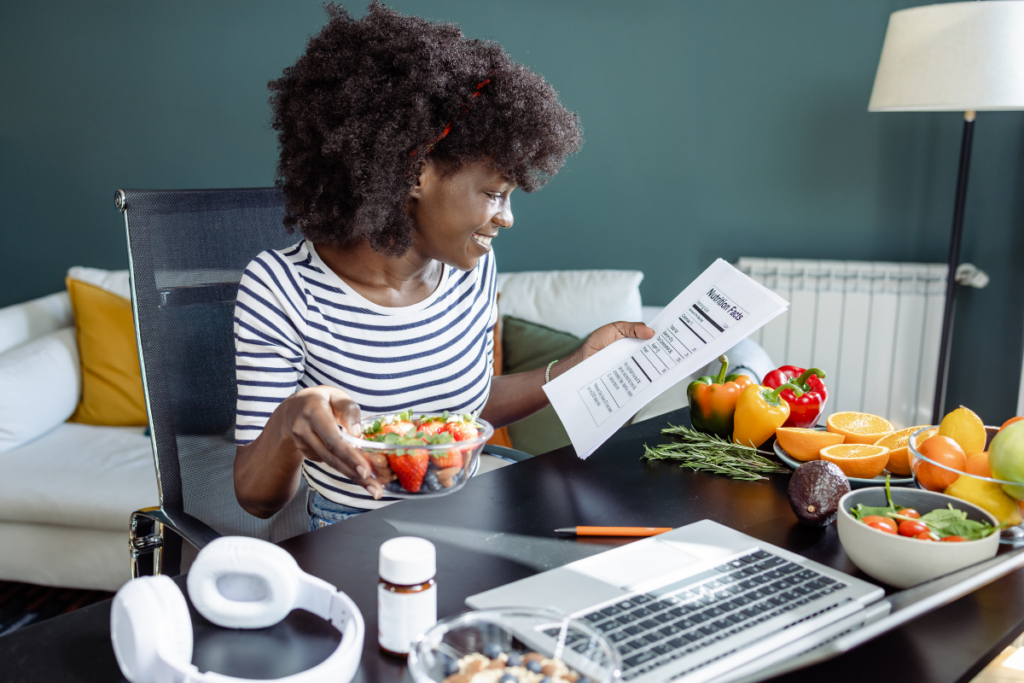 Woman sitting at a desk, studying nutrition labels and surrounded with fruits and veggies. 