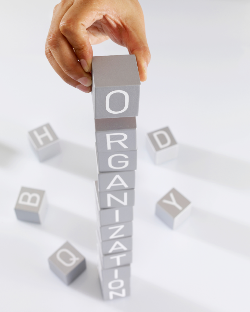 Hand stacking building blocks that spell out "organization".